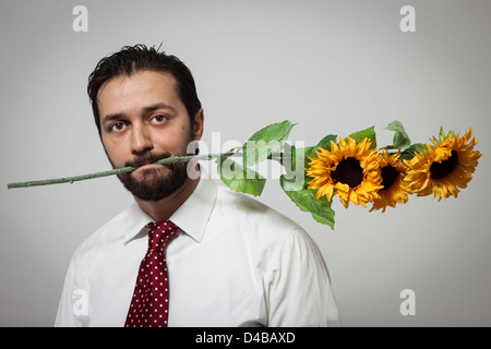 Porträt eines jungen bärtigen Mannes mit Sonnenblumen in den Mund Stockfoto