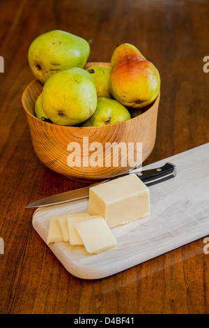 Eine Schale mit frischen Bartlett Birnen auf einem Holztisch mit Schnittkäse und ein Schälmesser auf ein Holz Schneidebrett Stockfoto