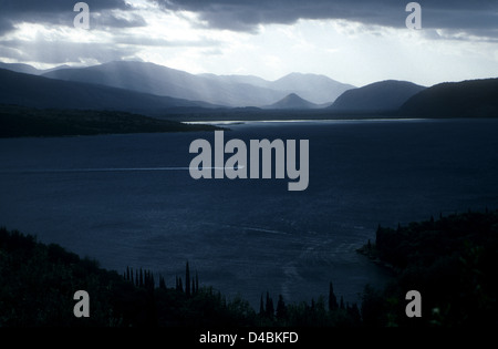 Die Sonnenstrahlen durchbrechen Gewitterwolken über Albanien über die Meerenge von Korfu aus Korfu zu sehen. Stockfoto