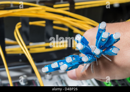 Hand des Administrators holding Bündel von Glasfaser-Kabel mit Steckern Stockfoto