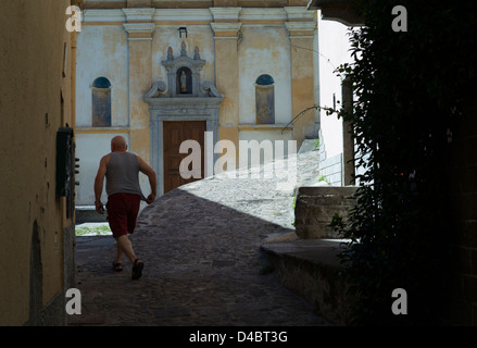 Italienische Seen, Comersee, Careno Dorf, Italien, Juli 2010. Dorfbewohner eilt Carenos kleine Straßen in Richtung der Pfarrkirche. Stockfoto