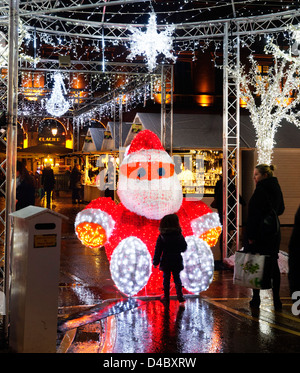 Ein kleines Mädchen Blick auf einen großen beleuchteten Weihnachtsmann auf dem Weihnachtsmarkt in Toulouse Stockfoto