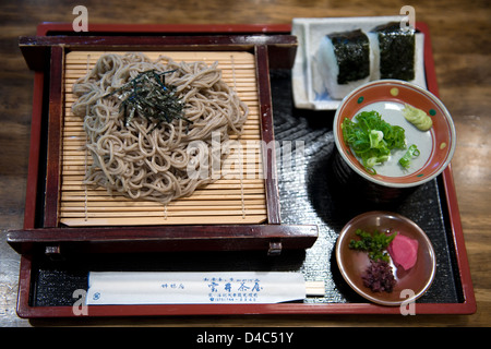 Mittagessen, japanischen Stil beinhaltet kalte Soba-Nudeln mit Nori, Otsukemono Gurken und zwei Onigiri-Reisbällchen. Stockfoto