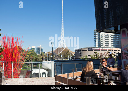 Menschen entspannen in bar am Federation Square mit Turm der Victorian Arts Centre im Hintergrund. Melbourne, Victoria, Australien Stockfoto