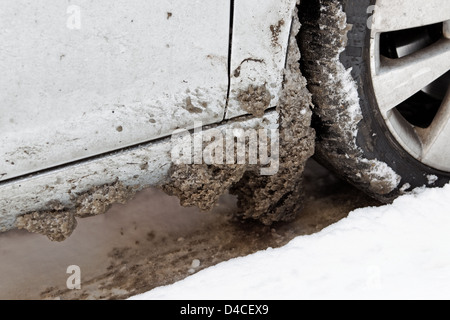 Schmutziger Schnee mit Salz in Auto Radbögen - Schlamm Klappen und