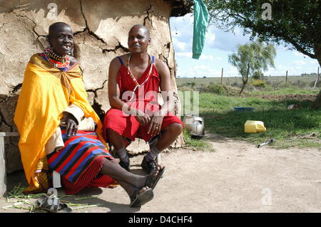 Zwei Männer der Masai Lächeln sitzen vor ihren Menschen traditionelle "Mayatta" Hütte im Kajiado District von Südkenia, 4. Dezember 2007. Die "Mayatta" ist für Touristen nur, die Massai Leben heute in "modernen" Shanties. Foto: Sandra Gaetke Stockfoto