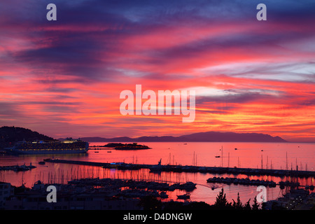 Roter Himmel Sonnenuntergang bei Kusadasi Türkei Hafen mit Schiff und guvercin adasi Schloss an der Ägäis mit Bergen von Samos Stockfoto