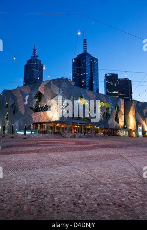 Federation Square in der Dämmerung mit Skyline der Stadt im Hintergrund beleuchtet. Melbourne, Victoria, Australien Stockfoto