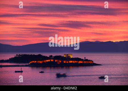 Roter Himmel Sonnenuntergang bei Kusadasi Türkei Hafen mit beleuchteten guvercin adasi Insel Burg auf die Ägäis mit Bergen von Samos, Griechenland Stockfoto