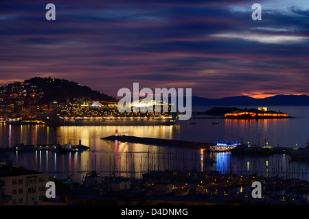 Kusadasi Türkei Hafen in der Abenddämmerung mit Guvercin Adasi Schloss und Kreuzfahrt Schiff an der Ägäis Stockfoto