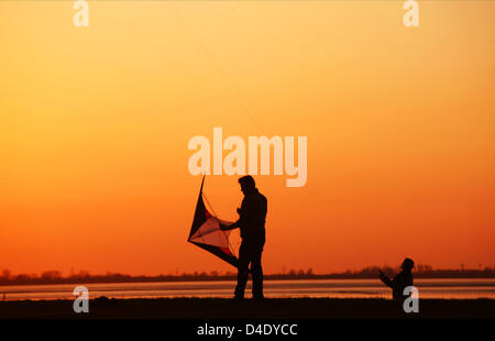 Zwei Männer Drachen im hellen orange Abendlicht an der Küste des Wattenmeeres in Dangast, Dollart-Region südlich von Wilhelmshaven, Deutschland, 22. April 2008. Foto: Wolfram Steinberg Stockfoto