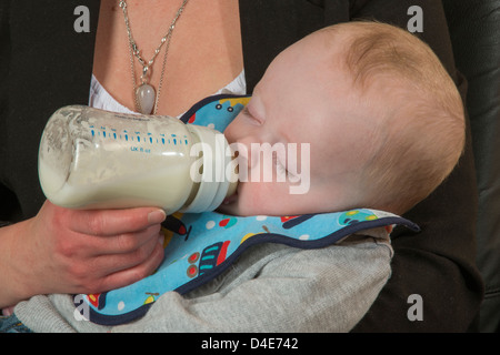 Baby Boy wird Flasche gefüttert durch seine junge Mutter sechs Monate altes Kind Stockfoto