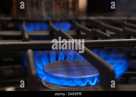 BLAUE FLAMME DER BELEUCHTETEN GASBRENNER RINGE AUF HERD BEREICH TOP Stockfoto
