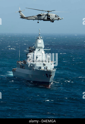 Ein uns Marine HH - 60H Sea Hawk-Hubschrauber fliegt über die deutsche Fregatte FGS Hamburg wie es das Mittelmeer mit Dwight D. Eisenhower Carrier Strike Group-11. März 2013 Transite. Stockfoto