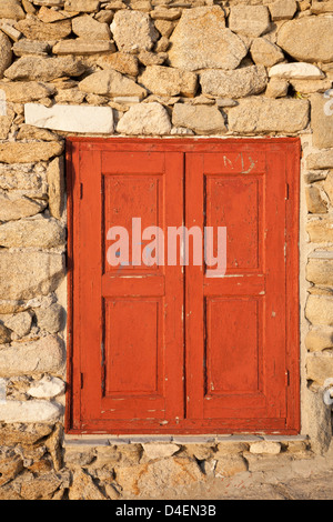 Verwitterte rote Holzläden in einem Steingebäude auf der griechischen Insel Mykonos Stockfoto