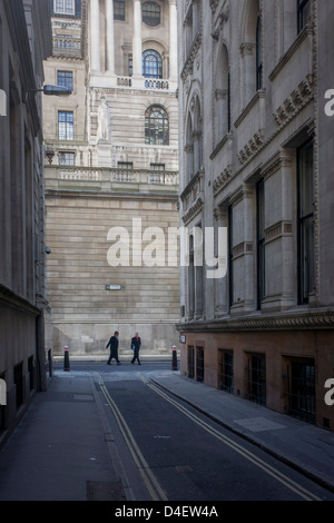 Zur Mittagszeit Fußgänger an der Ecke der Lothbury und Tokenhouse Hof, zwei engen historischen Gassen mit den hohen Mauern der Bank von England im Hintergrund - in der City of London, die Hauptstadt Bankenviertel. Das Gebiet wurde mit Kupferschmieden im Mittelalter besiedelt, bevor Sie später zu Heimat einer Reihe von Kaufleuten und Bankiers. Lothbury grenzt an die Bank of England auf der Nordseite des Gebäudes. Tokenhouse St stammt von Charles ich und war wo Farthing Token geprägt waren. Stockfoto