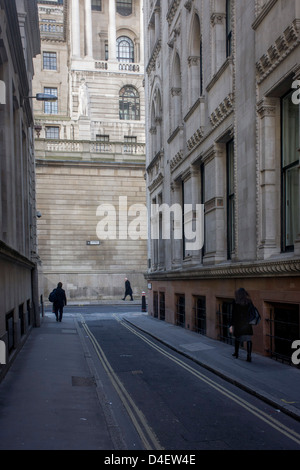 Zur Mittagszeit Fußgänger an der Ecke der Lothbury und Tokenhouse Hof, zwei engen historischen Gassen mit den hohen Mauern der Bank von England im Hintergrund - in der City of London, die Hauptstadt Bankenviertel. Das Gebiet wurde mit Kupferschmieden im Mittelalter besiedelt, bevor Sie später zu Heimat einer Reihe von Kaufleuten und Bankiers. Lothbury grenzt an die Bank of England auf der Nordseite des Gebäudes. Tokenhouse St stammt von Charles ich und war wo Farthing Token geprägt waren. Stockfoto