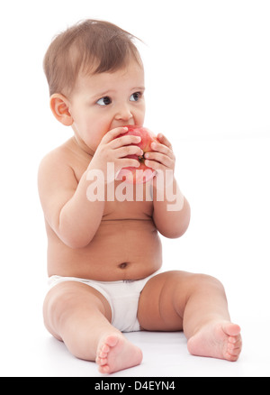 Lustiges Mädchen Baby auf dem Boden sitzt und isst einen Apfel. Isoliert auf weißem Hintergrund. Stockfoto