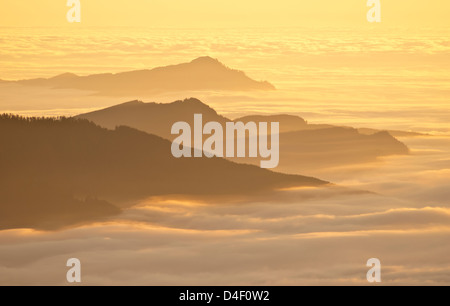 Luftaufnahme von Berggipfeln über den Wolken bei Sonnenuntergang Stockfoto