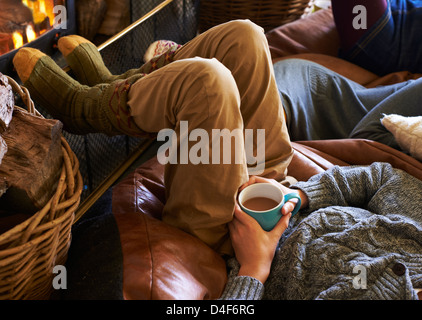 Junge, die Tasse Kaffee trinken, durch Feuer Stockfoto