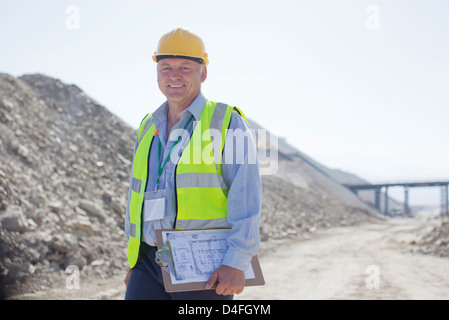 Geschäftsmann mit Zwischenablage im Steinbruch Stockfoto