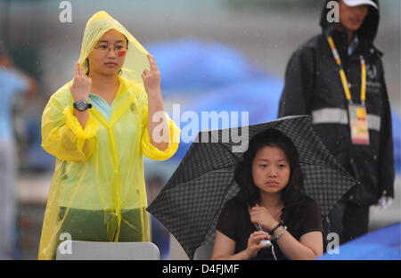 Zuschauer im Regen auf der Olympic Green Tenniszentrum während einer regen Verzögerung bei den 2008 Olympischen Spiele in Peking am National Aquatics Center in Peking 10. August 2008 stehen. Die 1. Vorrundenspiel ist Mens einzigen Tennis-Match von Nicolas Kiefer aus Deutschland und Max Mirnyi aus Belarus unhold wegen starken Regens. Foto: Karl-Josef Hildenbrand Dpa ## #dpa### Stockfoto