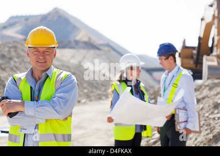 Unternehmer im harten Hut lächelnd im Steinbruch Stockfoto