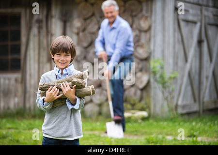 Jungen tragen Haufen Brennholz im freien Stockfoto