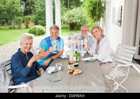 Freunde, die einander mit Wein am Tisch Toasten Stockfoto