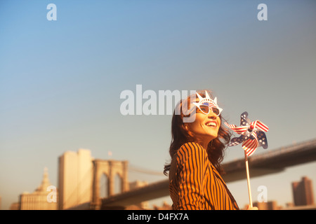 Frau-Neuheit-Sonnenbrille mit Windrad durch städtische Brücke Stockfoto