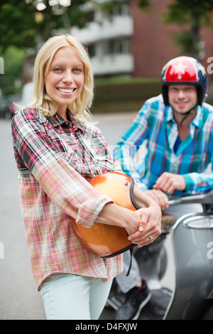 Lächelnde Frau hält Roller Helm Stockfoto