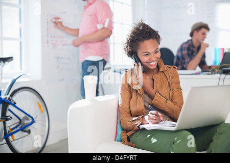 Geschäftsfrau, die Notizen am Telefon im Büro Stockfoto