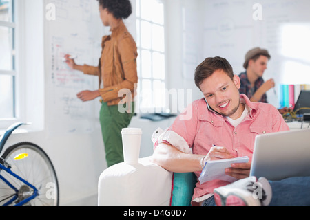 Geschäftsmann Notizen am Telefon im Büro Stockfoto