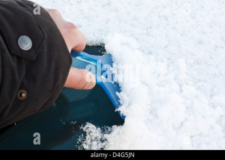 Clearing-Windschutzscheibe mit Eiskratzer nach starkem Schneefall für den sicheren Winter fahren auf der rechten Seite an einem frostigen Morgen mit Textfreiraum Stockfoto