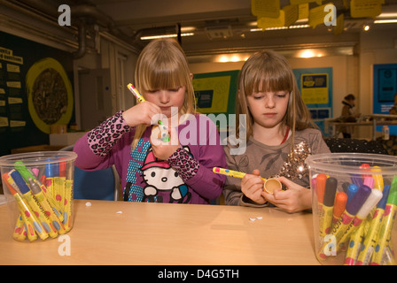 Zwei Schwestern, 6 & 7 Jahre alt, Malerei Eierbecher an einem eco station Tag der offenen Tür mit Hühnern, Bordon, Hampshire, UK. Stockfoto