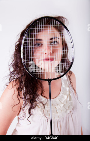 junge attraktive Brünette junge Frau hält einen Tennisschläger über ihr Gesicht Stockfoto