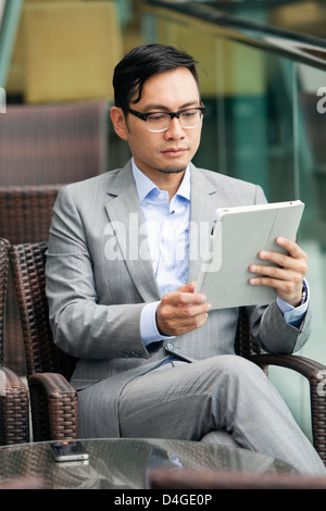 Ein junger chinesischer Geschäftsmann mit einem Tablet in Hong Kong. Stockfoto