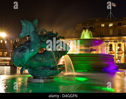 Trafalgar Square Brunnen beleuchtet in der Nacht mit Canada House und Fahne hinter West End London UK Stockfoto