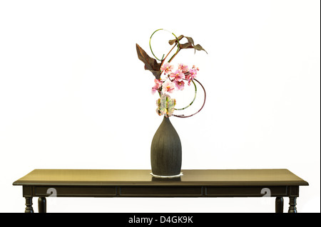 Blume in einem Glas auf Tisch mit weißem Hintergrund gefälscht Stockfoto