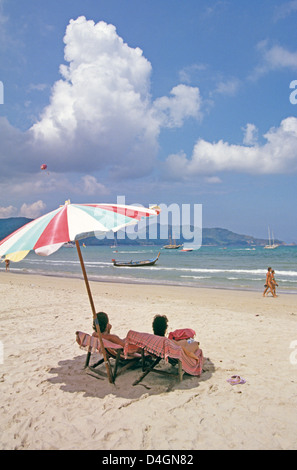 Urlaub paar Schatten selbst unter Sonnenschirm und beobachten Sie Strand Wirkstoffe am sandigen Strand von Phuket Stockfoto