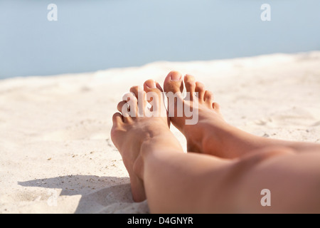 Bild der Füße der Frau beim Sonnenbaden am Sandstrand liegen Stockfoto