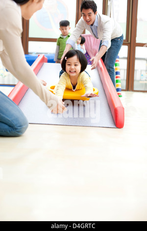 Fröhliches Mädchen hinunter eine Rutsche im kindergarten Stockfoto