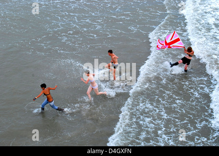 Junge Erwachsene spielen am Strand, Brighton, UK. Stockfoto