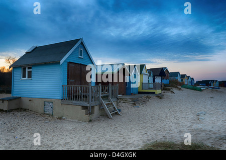 Strandhütten auf Mudeford Landzunge am Hengistbury Head in der Nähe von Christchurch kurz nach Sonnenuntergang. Stockfoto