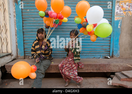 Zwei Kind Bettler ruhen Sie sich aus dem Verkauf von Ballons in Mathura, West Uttar Pradesh, Indien Stockfoto