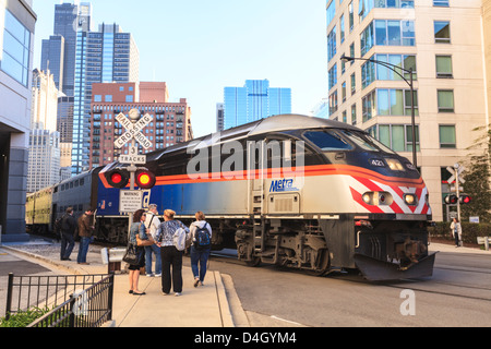 Metra Zug vorbei an Fußgänger an einer offenen Bahnübergang, Downtown, Chicago, Illinois, USA Stockfoto