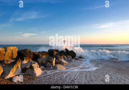 Wellen schlagen eine Buhne Meer und Felsen am Strand von Hengistbury Head in der Nähe von Bournemouth in Dorset Stockfoto