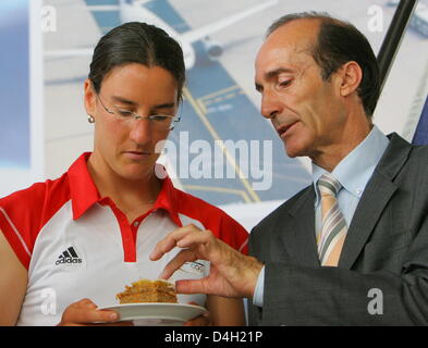 Deutscher Fußballspieler Birgit Prinz (L) erhält einen Stück Kuchen vom DOSB (Deutsche Olympische Sportbund) Vizepräsident Eberhard Gienger vor ihrer Abreise nach Peking am Flughafen in Frankfurt Main, Deutschland, 30. Juli 2008. Einige 80 Mitglieder der Ruder Nationalmannschaft und die Frauen-Fußball-Nationalmannschaft wurden offiziell von Vertretern des DOSB, Deutsch aus gesehen Stockfoto