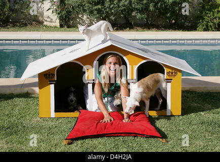 Maja Synke Prinzessin von Hohenzollern posiert mit ihrem Hund "Bambi" und ihre Katze "Mutzel" in eine Hundehütte entworfen von sich selbst in einem Garten in Marbella, Spanien, 26. Juli 2008. Maja von Hohenzollern lebt in einem Haus in Andalusien mit fünf Welpen, fünf Hunde und zwei Katzen, die sie von der Straße oder der Tötung Station gerettet hat. Maja von Hohenzollern verkauft ihre gestalteten Tierhäuser eine Stockfoto