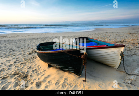 Angelboote/Fischerboote an einem Sandstrand in Bournemouth mit alten harry Felsen und der Isle of Purbeck in der Ferne. Stockfoto